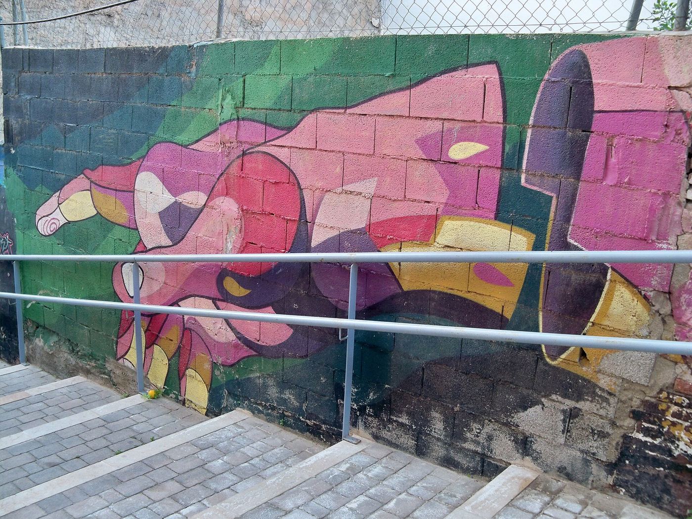 Large pink and green mural of a hand painted beside an outdoor stairway