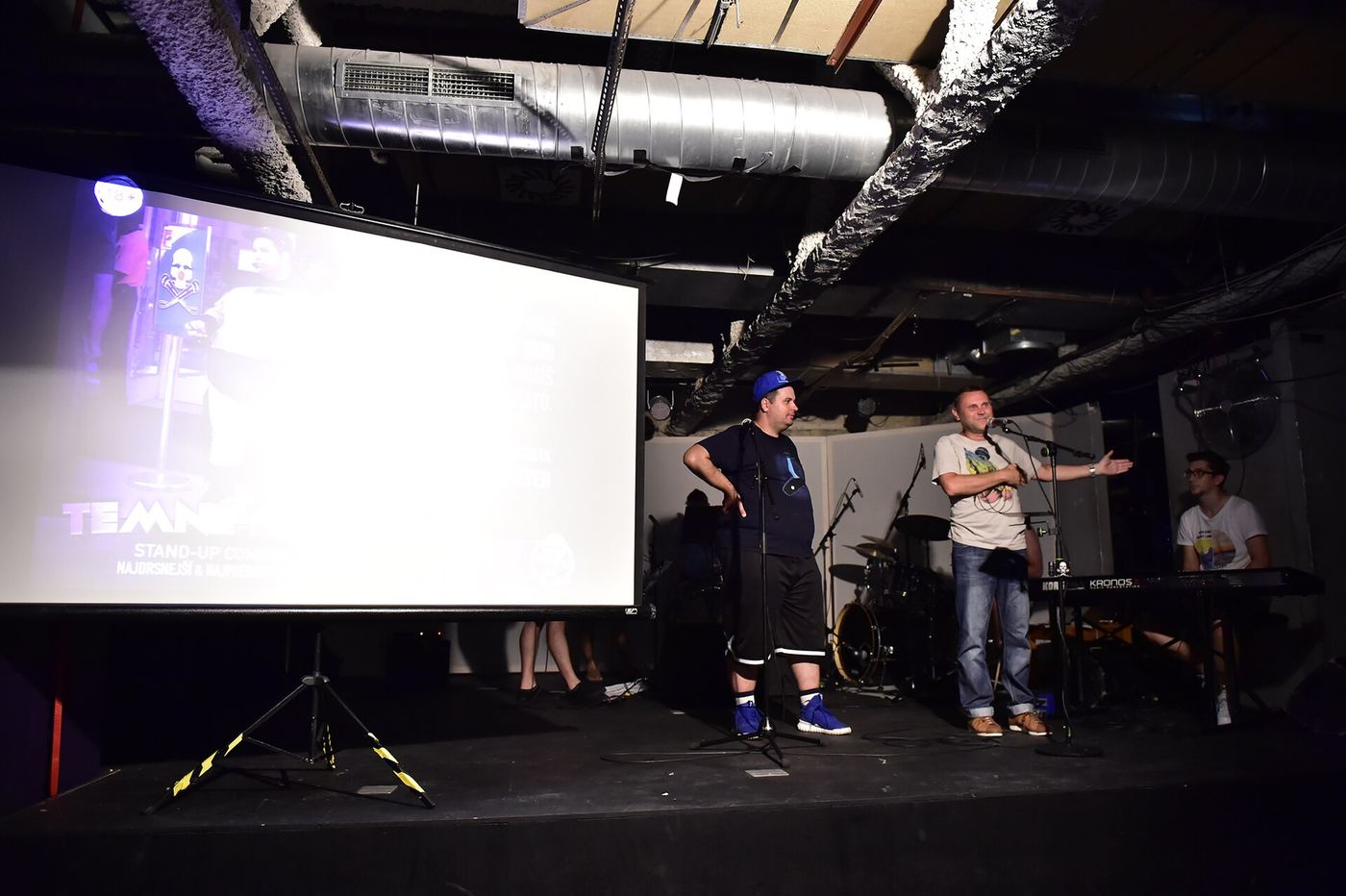 Speakers on a dark stage in front of a projection screen